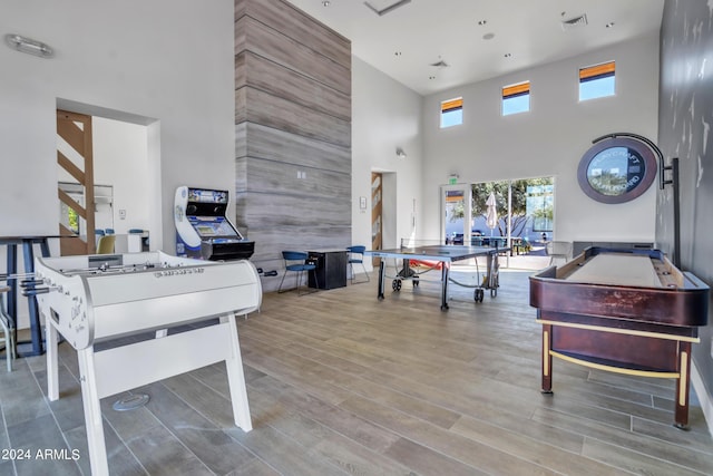 recreation room with hardwood / wood-style flooring and a towering ceiling