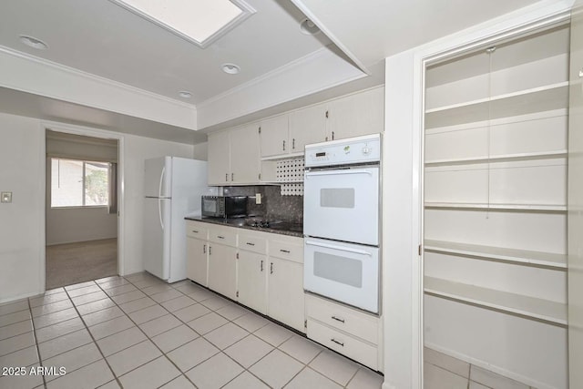 kitchen featuring light tile patterned floors, decorative backsplash, black appliances, dark countertops, and a raised ceiling