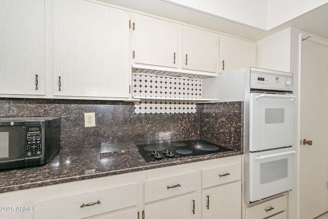 kitchen with black appliances, tasteful backsplash, and dark stone counters