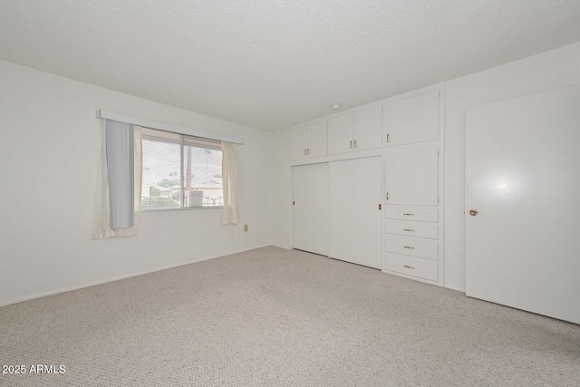 unfurnished bedroom with a textured ceiling, a closet, and light carpet