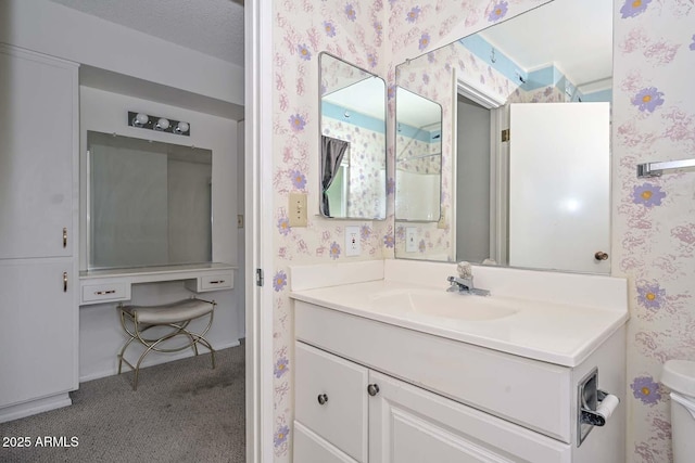 bathroom featuring toilet, vanity, and wallpapered walls