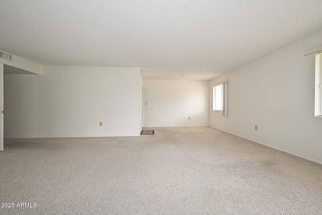 spare room featuring visible vents, carpet, and a textured ceiling