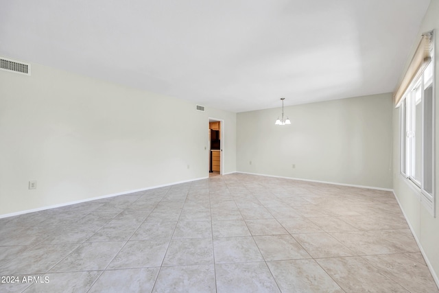 tiled spare room with a chandelier