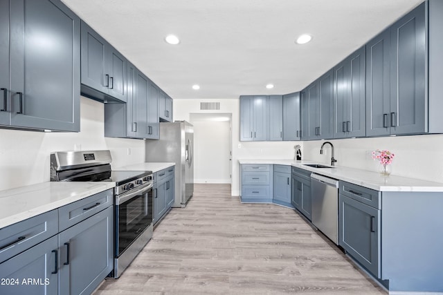 kitchen featuring light stone countertops, appliances with stainless steel finishes, light wood-type flooring, and sink