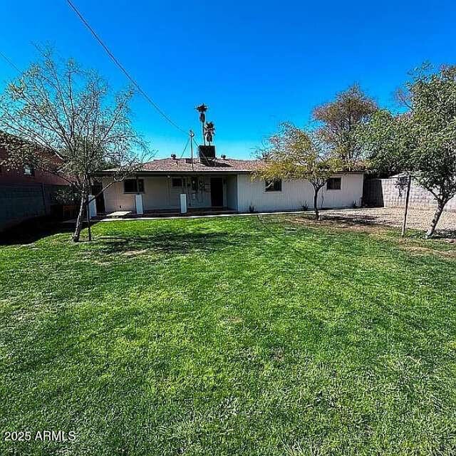 rear view of house with a yard and fence