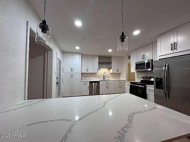 kitchen with recessed lighting, a sink, appliances with stainless steel finishes, pendant lighting, and tasteful backsplash
