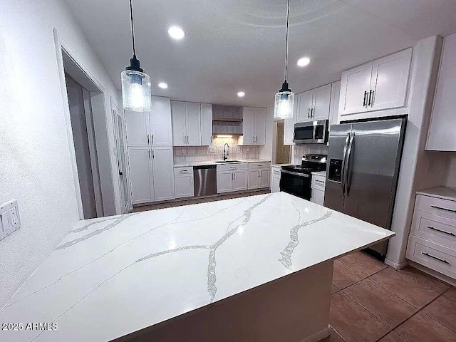 kitchen featuring pendant lighting, light stone countertops, tasteful backsplash, and stainless steel appliances