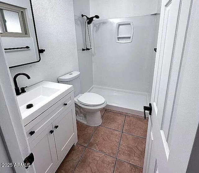 bathroom with tile patterned floors, toilet, a shower stall, vanity, and a textured wall