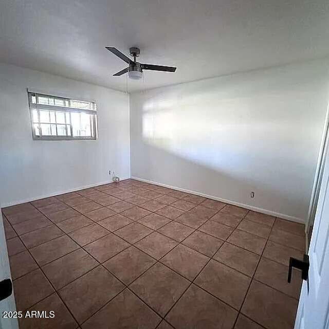empty room with tile patterned flooring and a ceiling fan