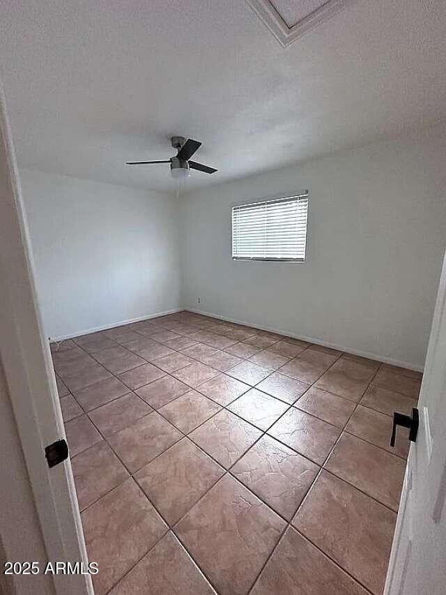 tiled empty room featuring a textured ceiling and ceiling fan