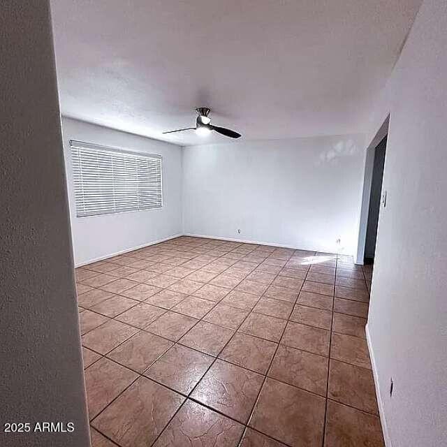 empty room featuring tile patterned floors and a ceiling fan