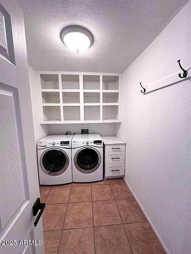 laundry area featuring tile patterned floors, independent washer and dryer, a textured ceiling, laundry area, and a textured wall