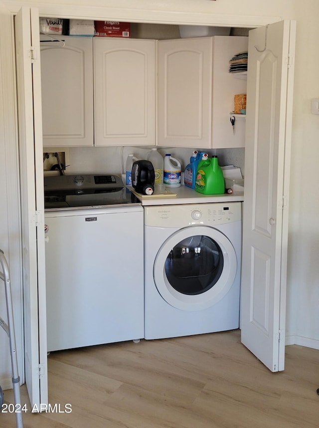 clothes washing area featuring light hardwood / wood-style floors, cabinets, and washer and clothes dryer