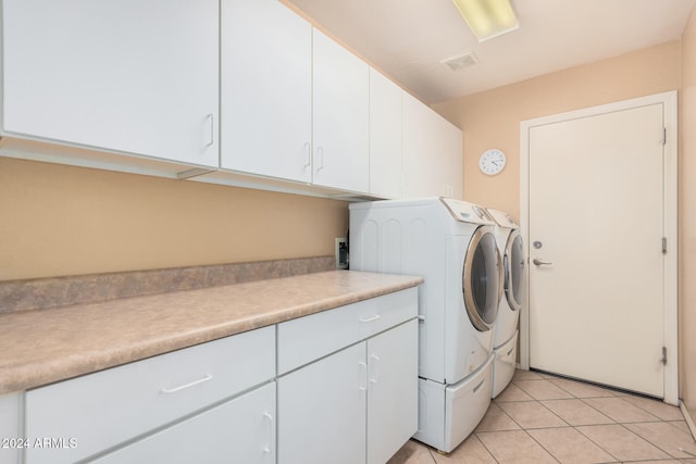 laundry area featuring washer and clothes dryer, cabinets, and light tile patterned flooring