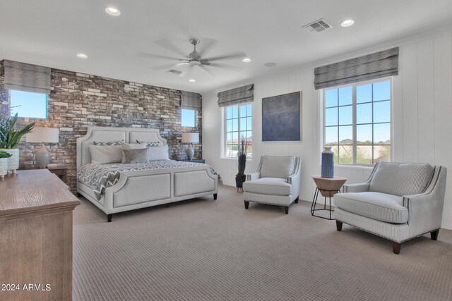 carpeted bedroom with ceiling fan and wood walls