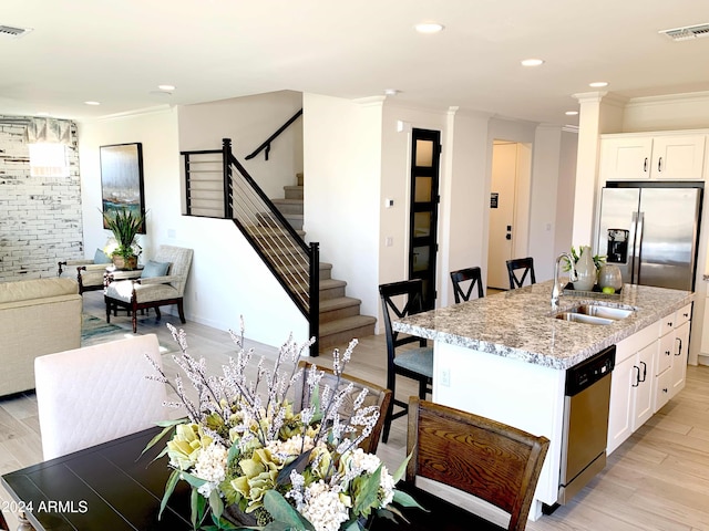 kitchen with appliances with stainless steel finishes, light wood-type flooring, white cabinetry, and sink