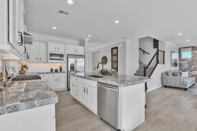 kitchen with a center island with sink, white cabinets, sink, and stainless steel appliances