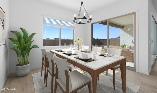 dining space with a notable chandelier, baseboards, and light wood finished floors
