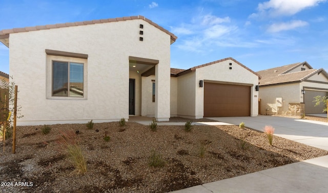 view of front of property with stucco siding, an attached garage, a tiled roof, and concrete driveway