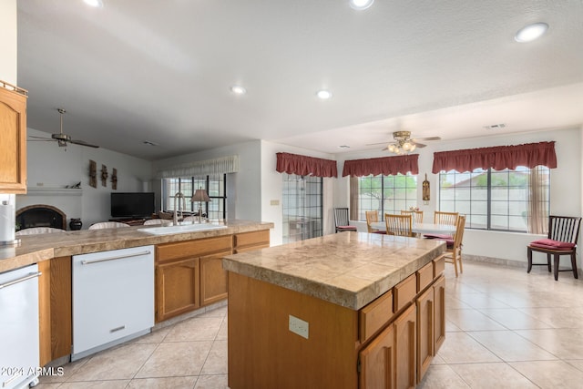 kitchen with light tile floors, a center island, ceiling fan, dishwasher, and sink