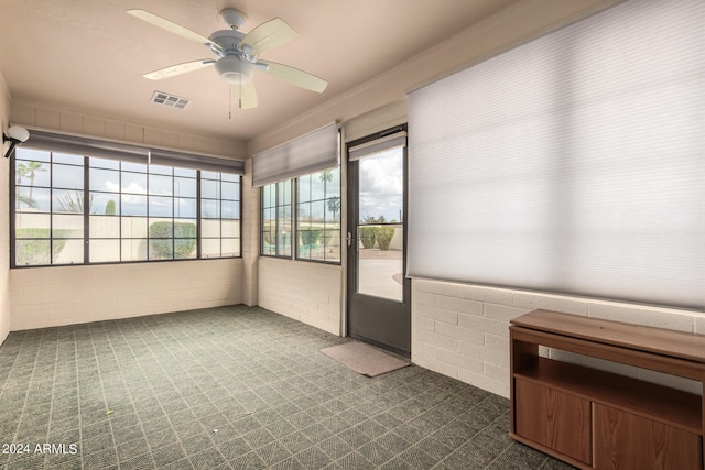 unfurnished sunroom with ceiling fan