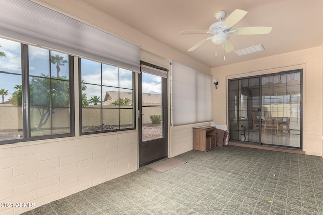 unfurnished sunroom featuring ceiling fan