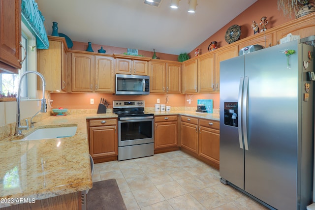 kitchen with light stone counters, light tile patterned flooring, stainless steel appliances, sink, and lofted ceiling