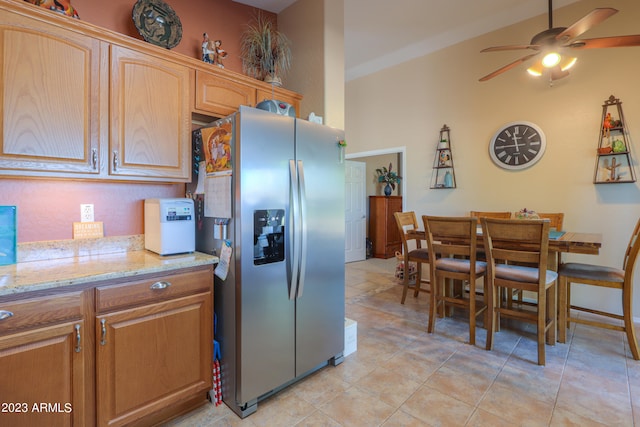 kitchen featuring light tile patterned flooring, light stone countertops, ceiling fan, lofted ceiling, and stainless steel fridge