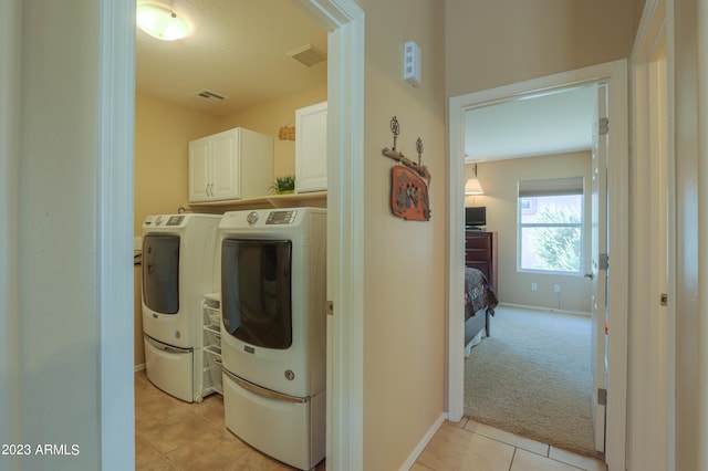 clothes washing area with cabinets, light tile patterned floors, and separate washer and dryer