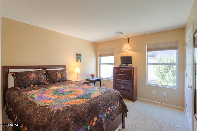 bedroom featuring light colored carpet and multiple windows