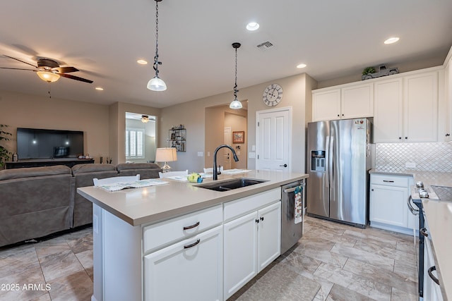 kitchen with sink, hanging light fixtures, stainless steel appliances, an island with sink, and white cabinets