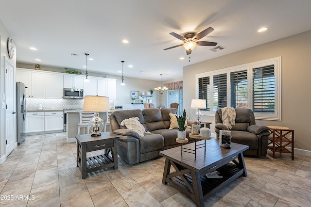 living room with ceiling fan with notable chandelier