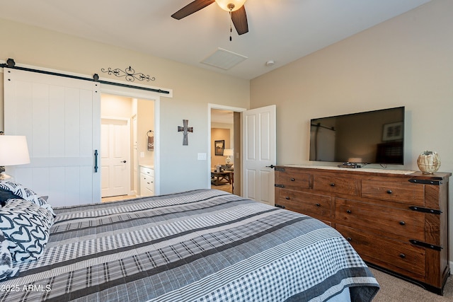 carpeted bedroom with a barn door, ceiling fan, and connected bathroom