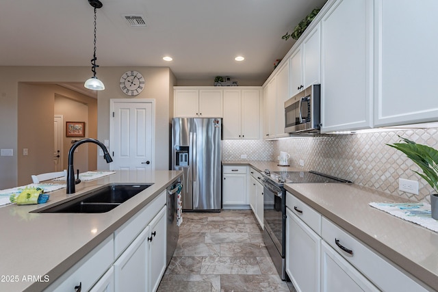 kitchen with decorative light fixtures, white cabinetry, sink, and appliances with stainless steel finishes