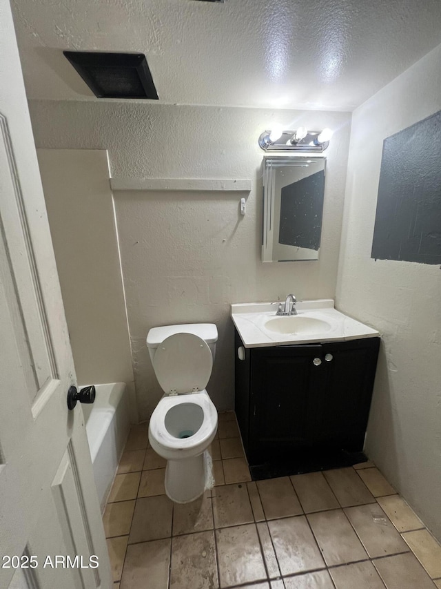 bathroom featuring a bathtub, vanity, toilet, tile patterned floors, and a textured ceiling