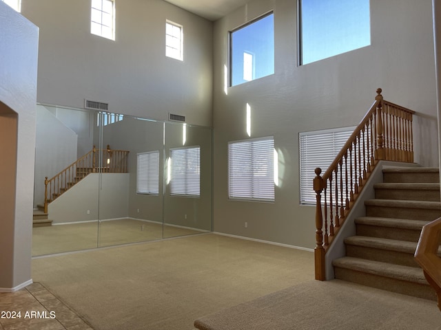 unfurnished living room with carpet flooring and a towering ceiling