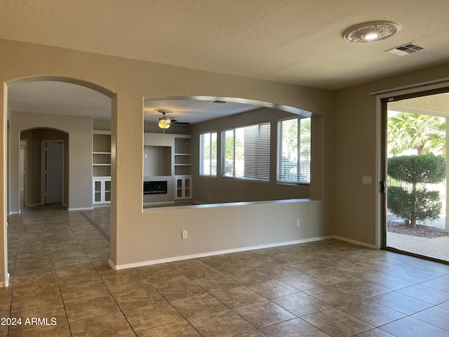 interior space featuring a textured ceiling, built in features, and ceiling fan