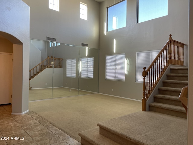 carpeted foyer entrance featuring a towering ceiling