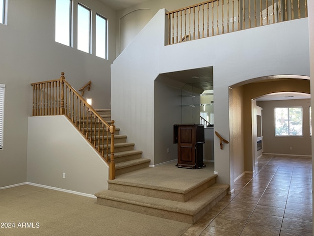 stairs with tile patterned floors and a high ceiling