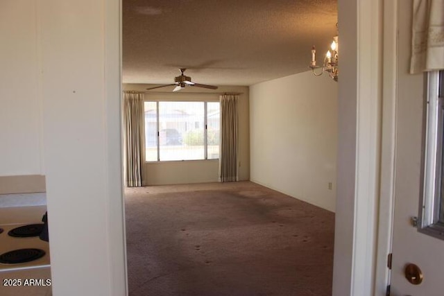 empty room featuring ceiling fan with notable chandelier, carpet floors, and a textured ceiling