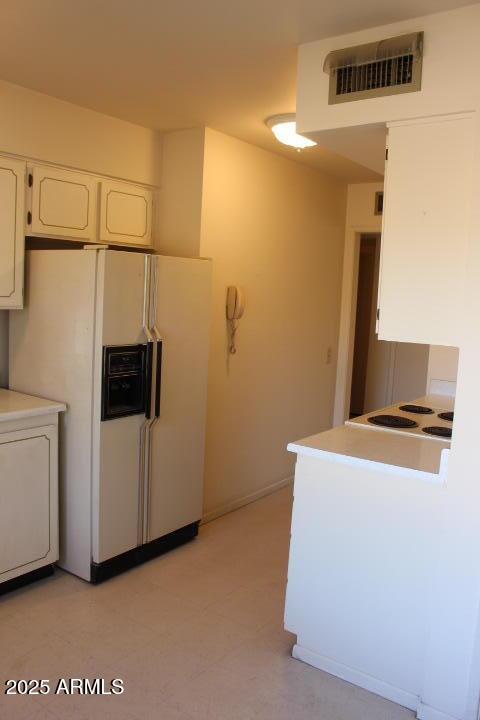 kitchen featuring white cabinetry, white refrigerator with ice dispenser, and stovetop