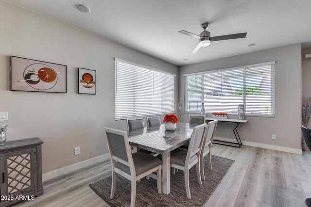 dining area with a ceiling fan, baseboards, and light wood-style floors