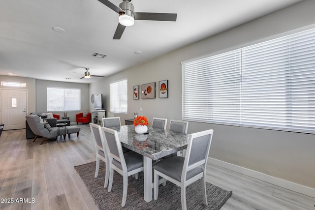 dining area featuring baseboards, a ceiling fan, and light wood-style floors