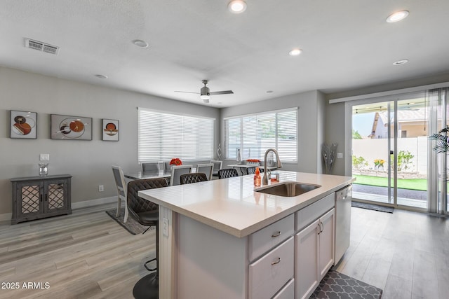 kitchen featuring light countertops, visible vents, a sink, light wood-style flooring, and ceiling fan