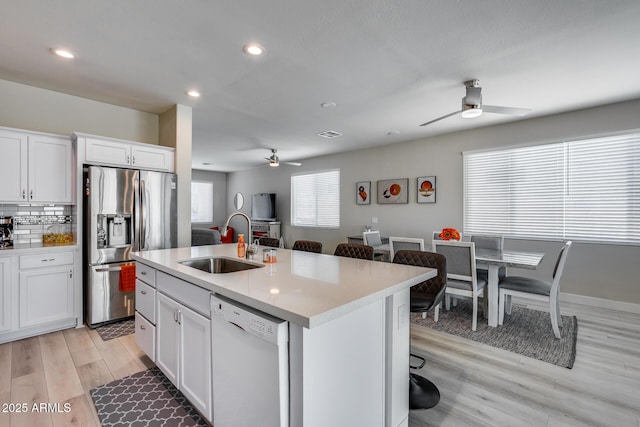 kitchen with a ceiling fan, a sink, light wood-type flooring, dishwasher, and stainless steel fridge with ice dispenser
