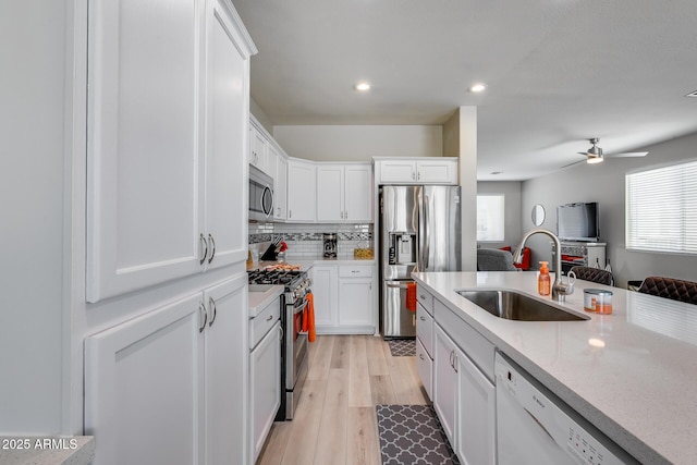 kitchen with stainless steel appliances, a sink, and white cabinetry