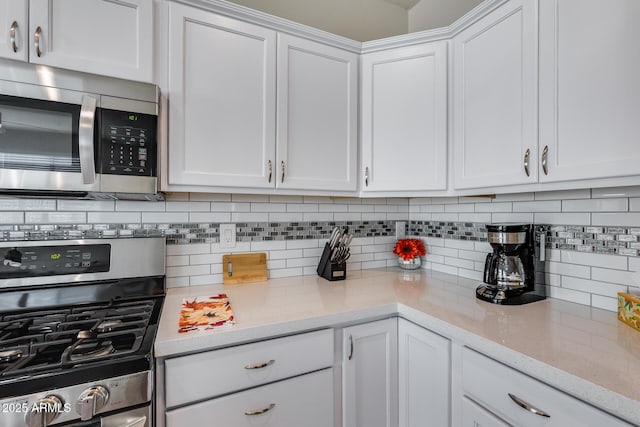 kitchen featuring white cabinets, stainless steel appliances, light stone countertops, and tasteful backsplash