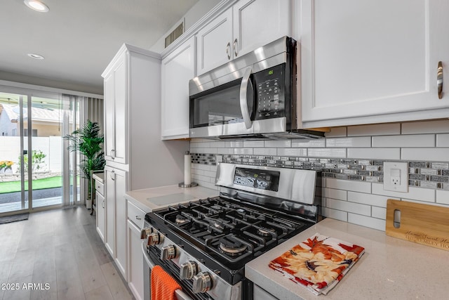 kitchen with stainless steel appliances, recessed lighting, backsplash, white cabinetry, and light countertops