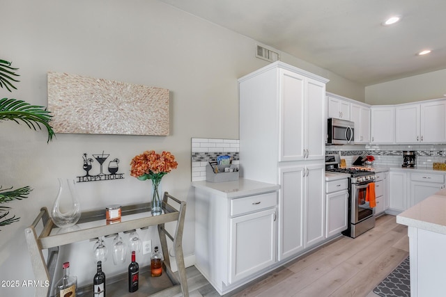 kitchen with tasteful backsplash, light countertops, appliances with stainless steel finishes, visible vents, and recessed lighting