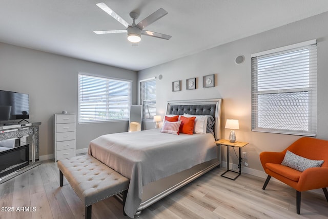 bedroom with ceiling fan, baseboards, and light wood finished floors